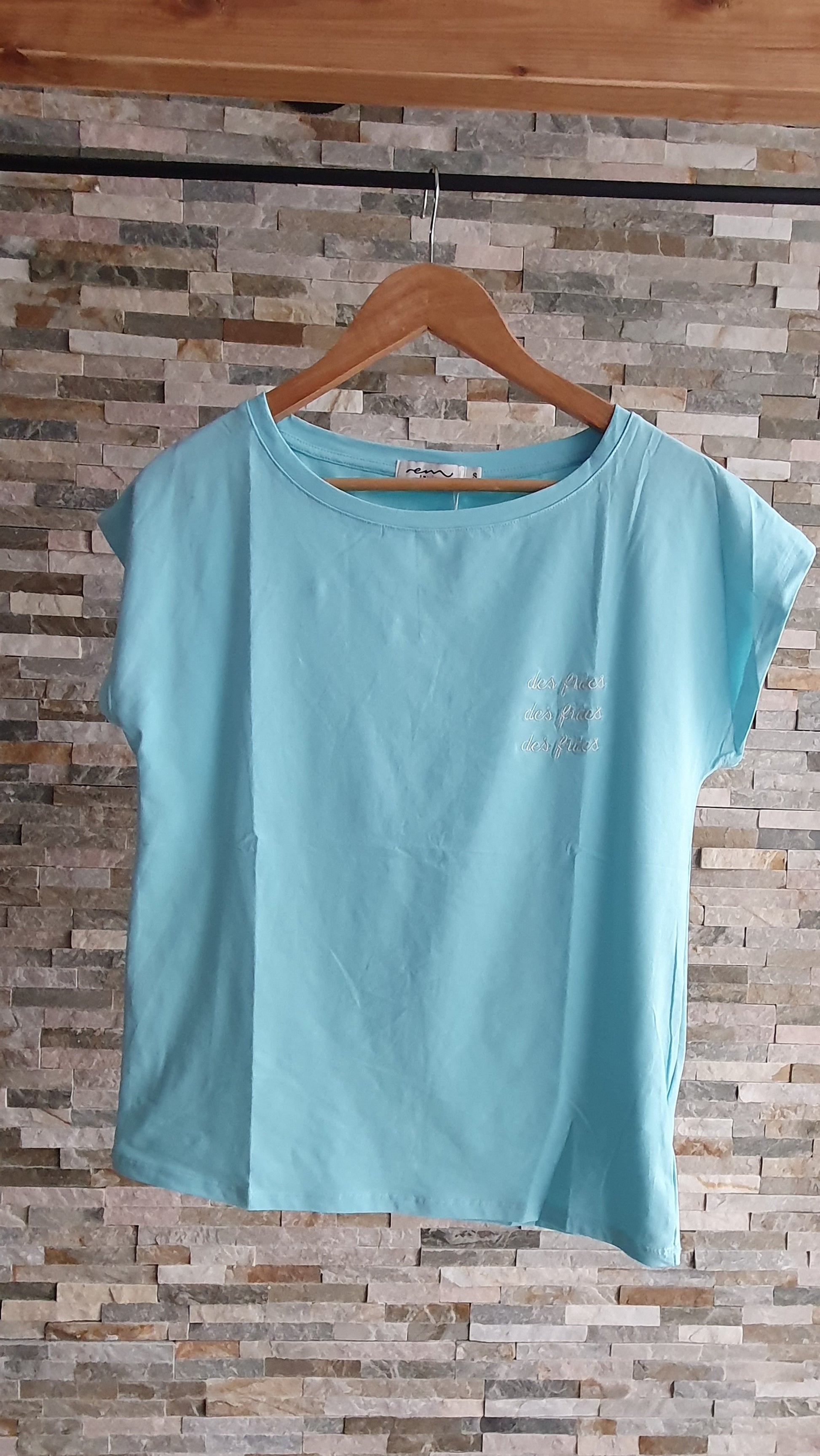 Tee-shirt turquoise comprenant des inscriptions : des frites , des frites , des frites